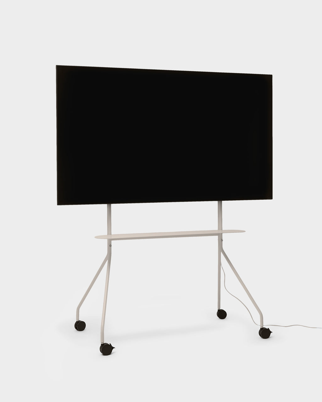 Moon PRO TV stand in Oat holding a large flat-screen TV, angled studio view showing shelf, tripod legs and casters