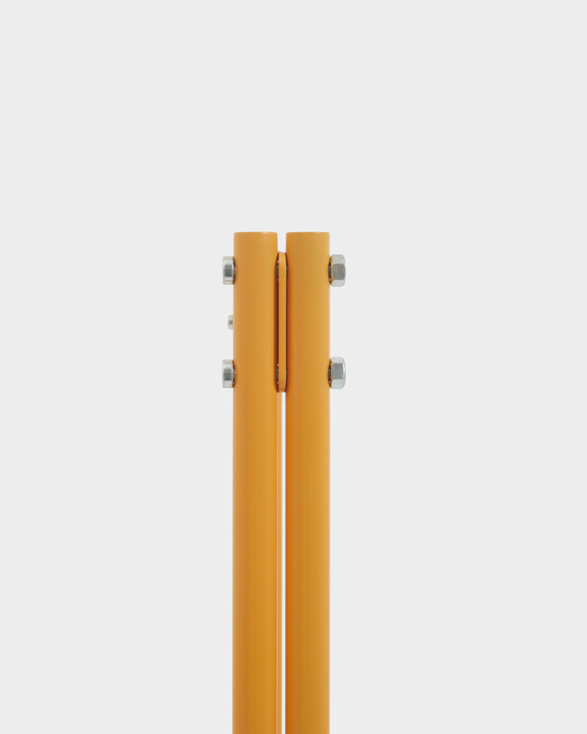 Close-up studio detail of the Moon in Apricot stand's twin apricot poles joined by chrome bolts against a light gray backdrop