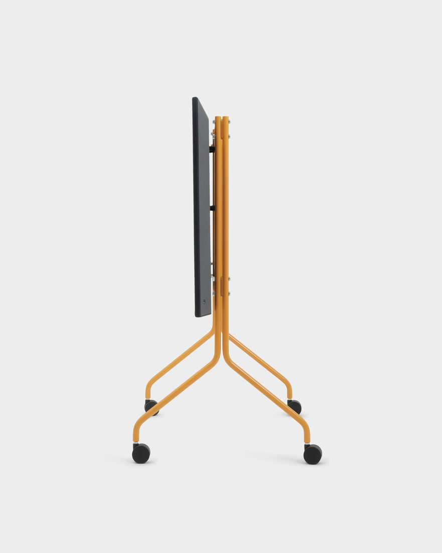 Side profile studio shot of the Moon stand in Apricot, folded flat with dark panel and four black caster wheels