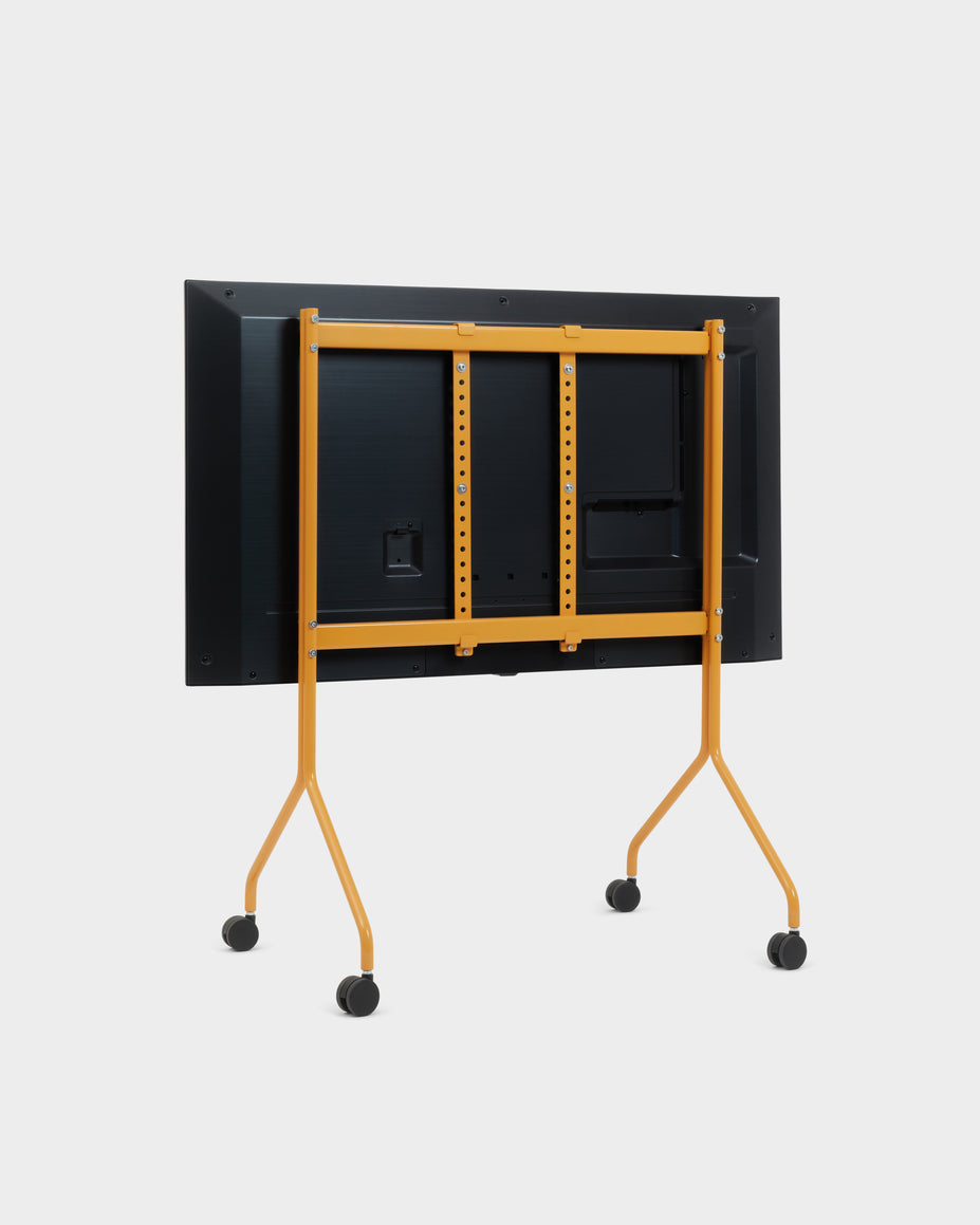 Rear view of the Moon rolling TV stand in Apricot holding a mounted flat-screen display, studio packshot with locking wheels