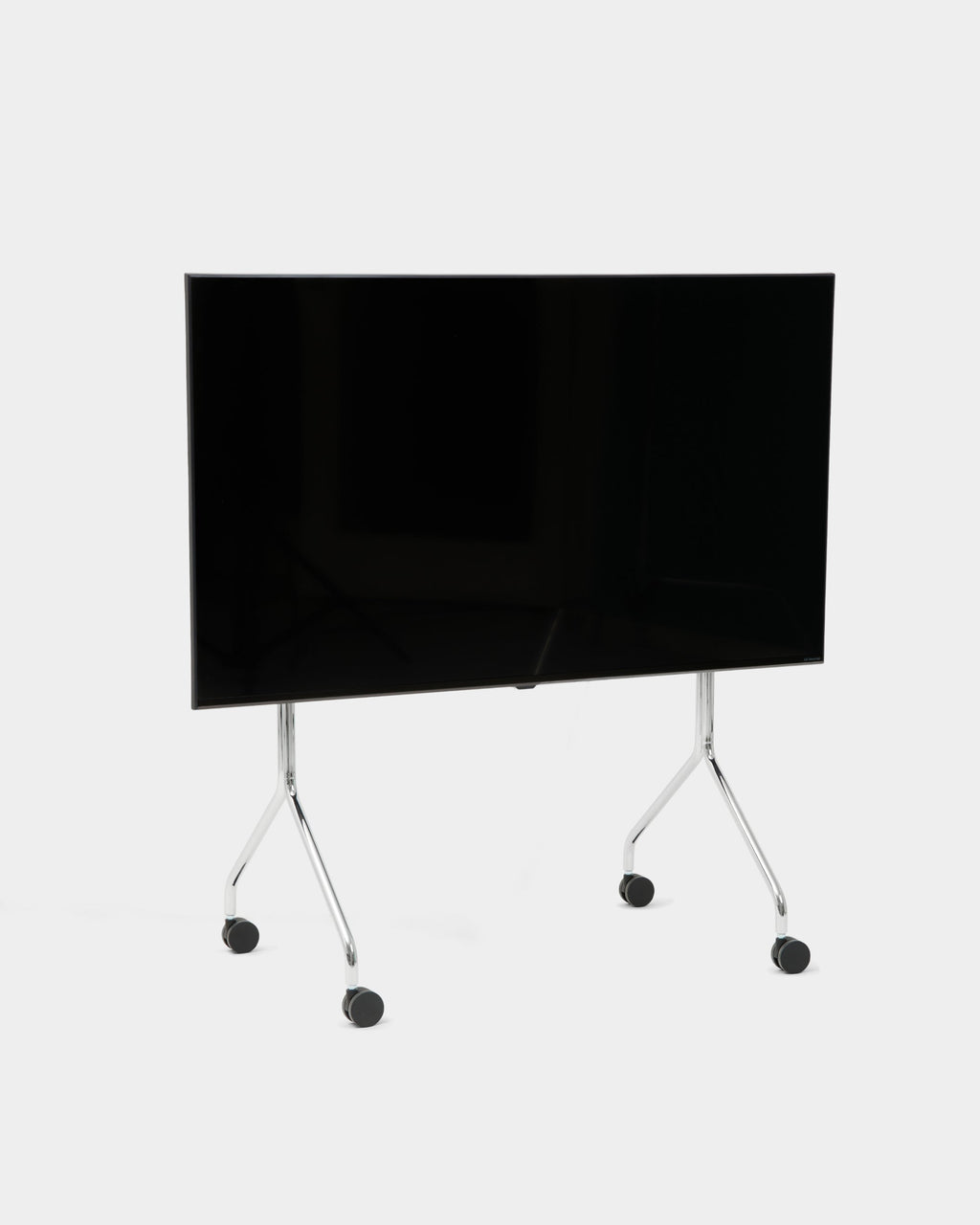Moon TV stand in Chrome holding a large flat-screen TV, angled studio view showing splayed legs and black wheels
