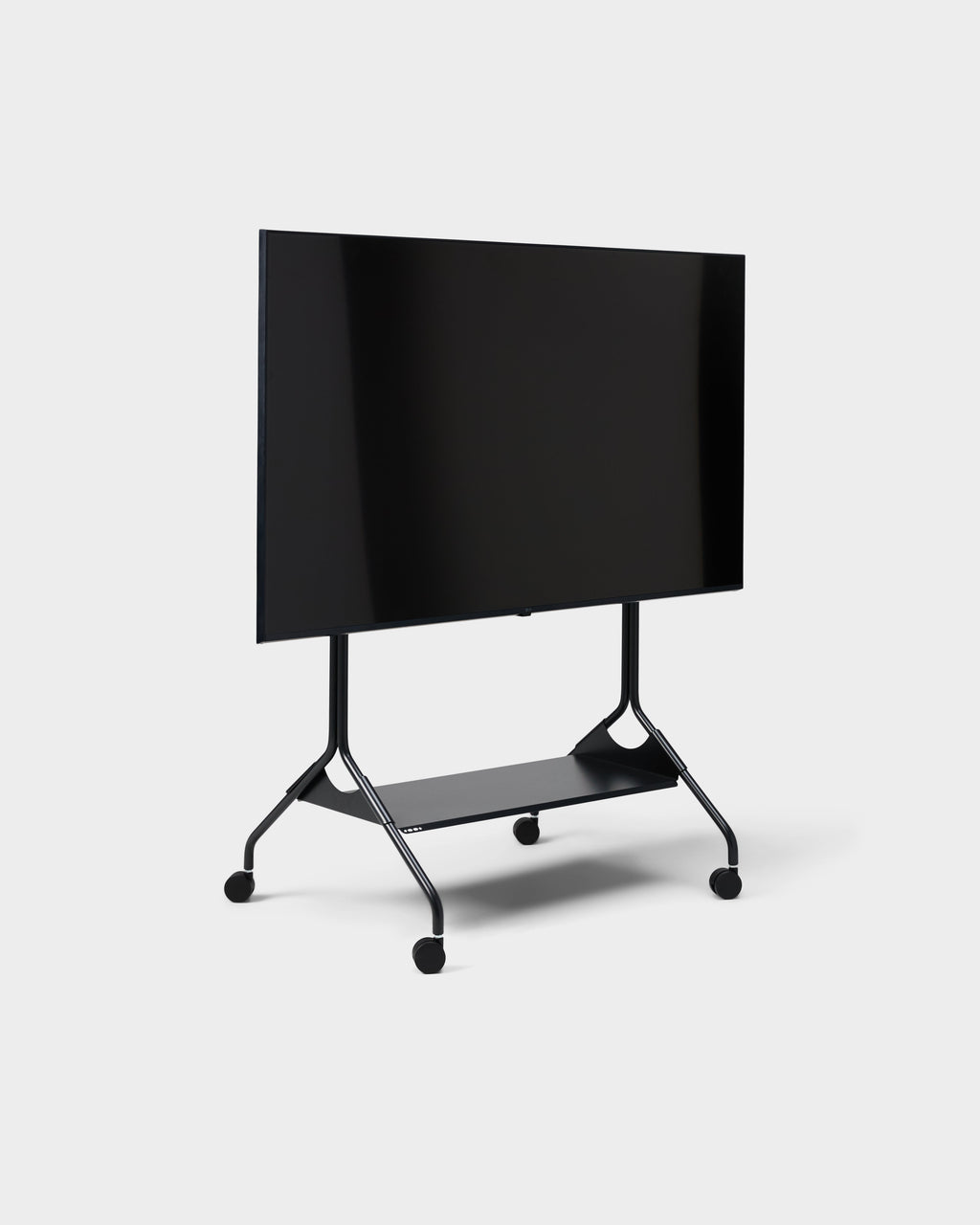 Angled studio view of the Moon Tall stand in Charcoal with mounted TV, lower shelf and locking wheels on white