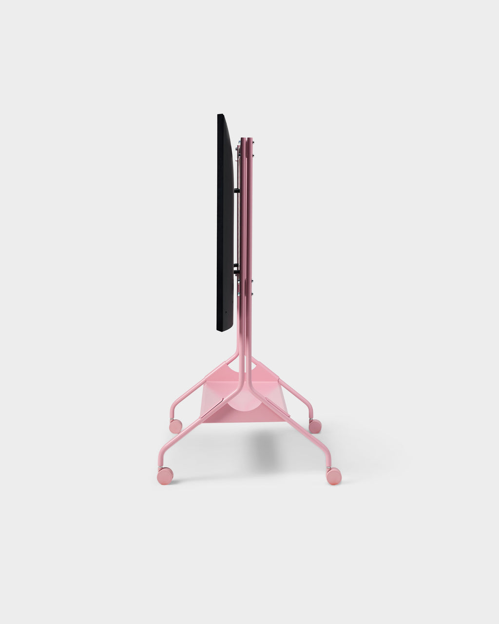 Side profile of the Moon Tall stand in Bubble Gum pink with mounted TV and rolling wheels on a studio backdrop