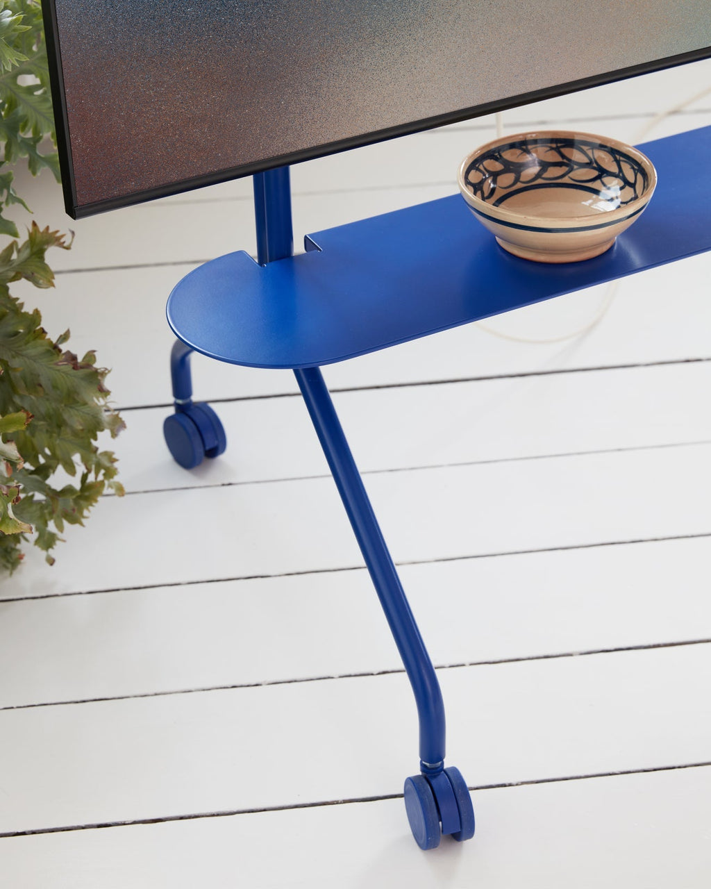 Ultra Marine Wheels TV stand on white deck, close-up of castors and blue shelf holding a ceramic bowl