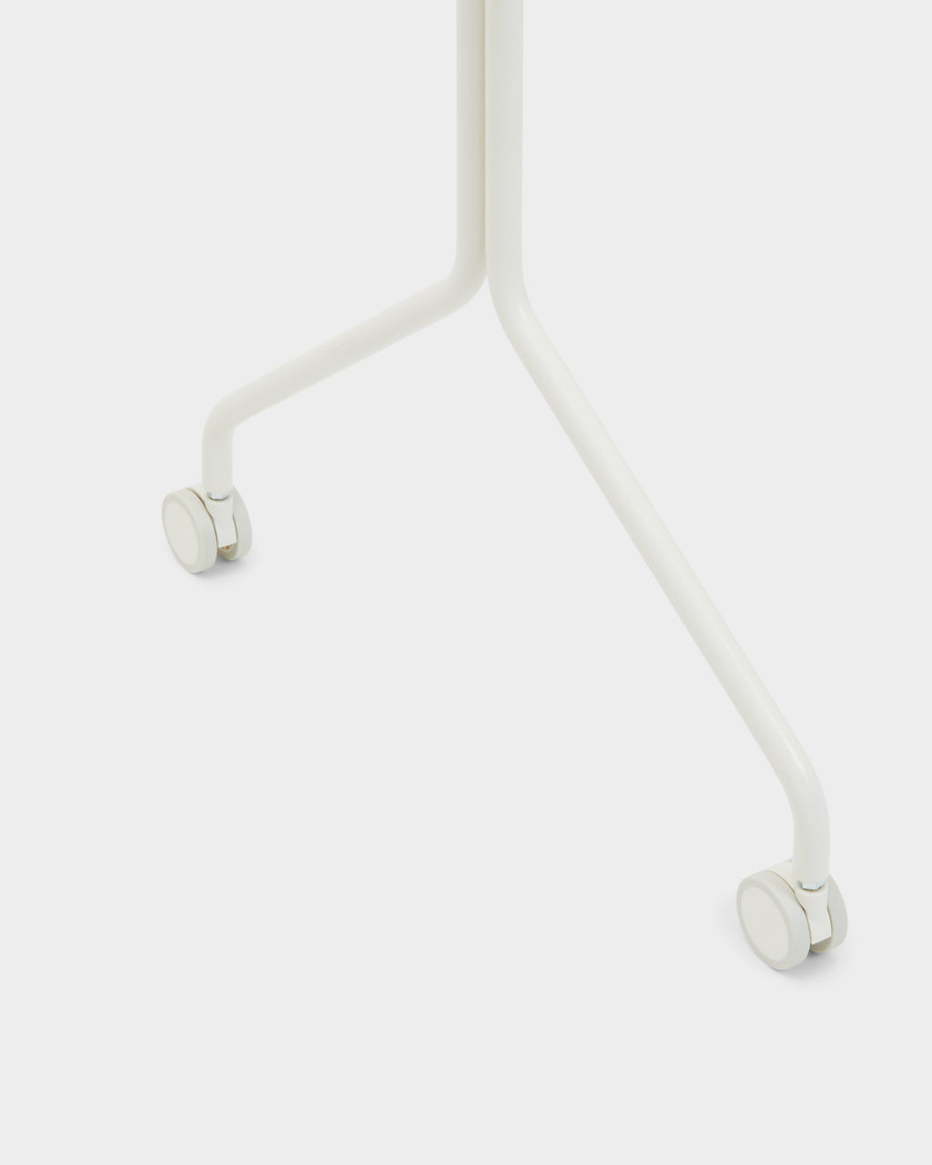 Close-up of Wheels in Pearl showing the curved white tubular legs and swivel casters against a studio backdrop