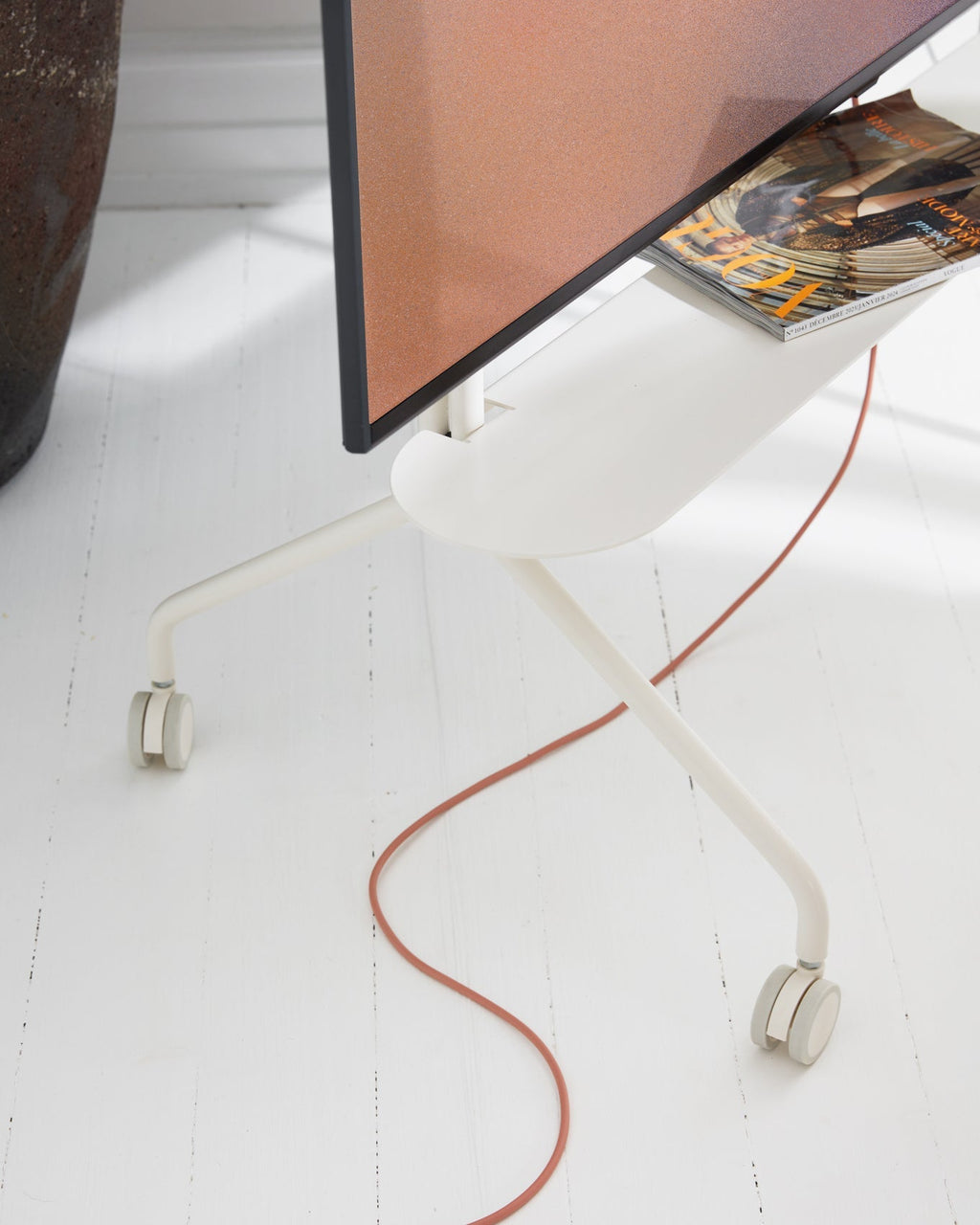 Wheels in Pearl on white plank floor, close angle on castors, shelf with magazines and terracotta cable
