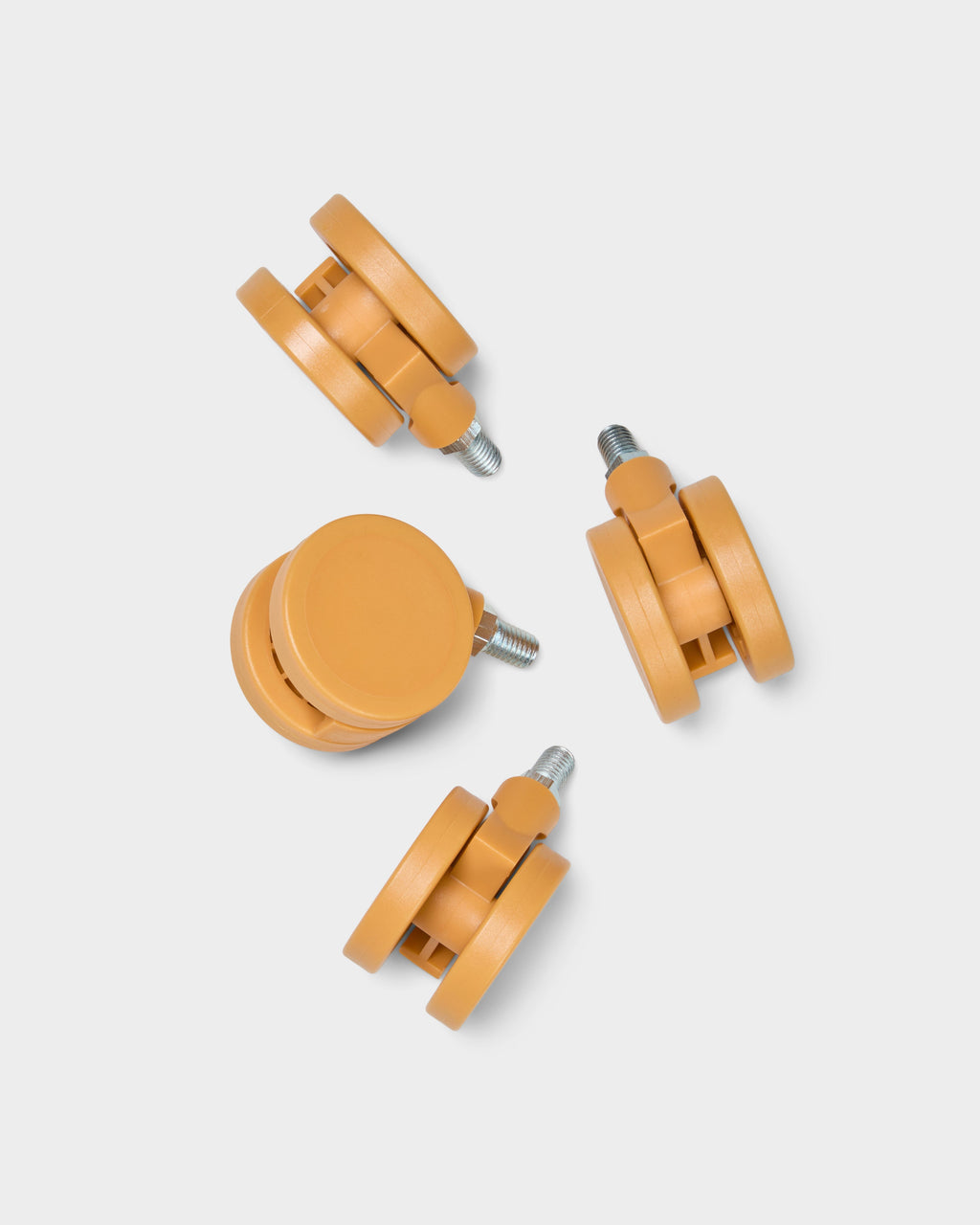 Set of four apricot Wheels casters with threaded metal stems, arranged on a light grey studio background