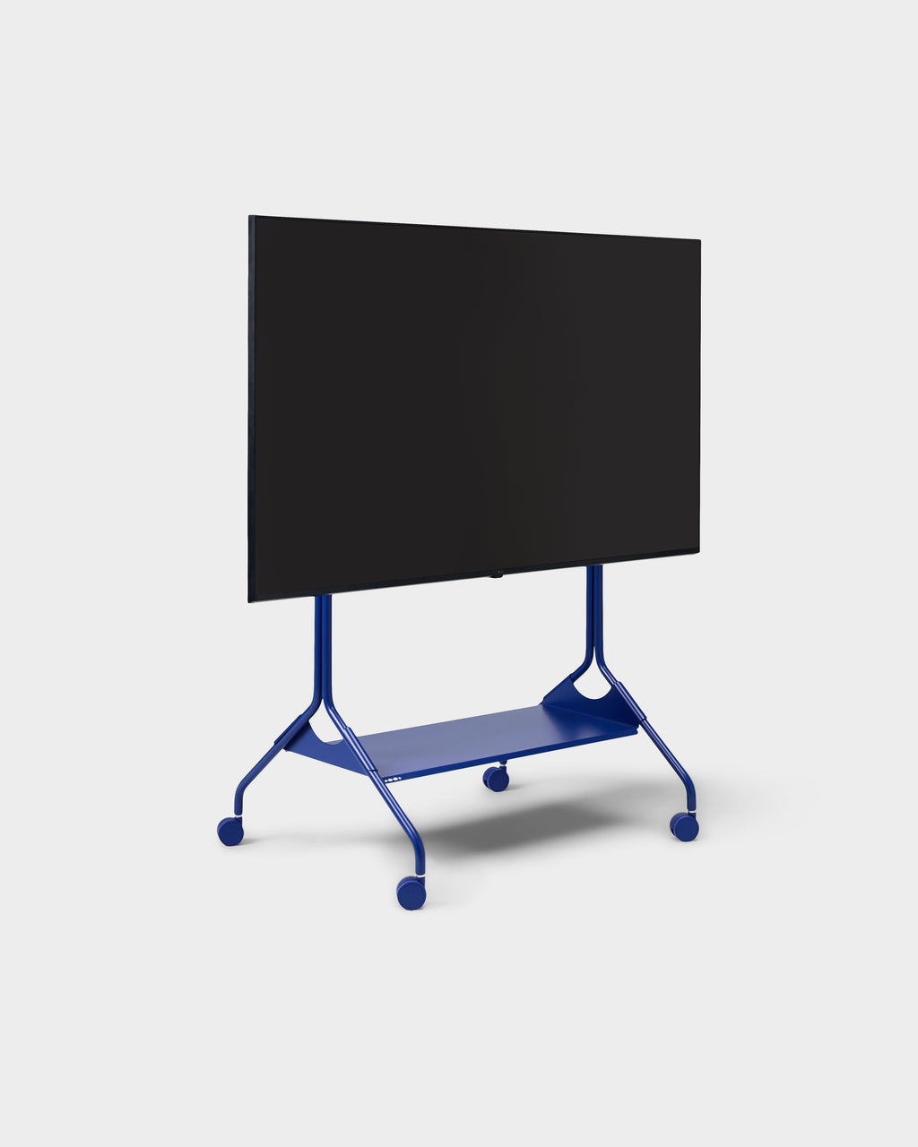 Angled studio view of Moon Tray Shelf in Ultra Marine on a rolling TV stand with casters, flat screen mounted above