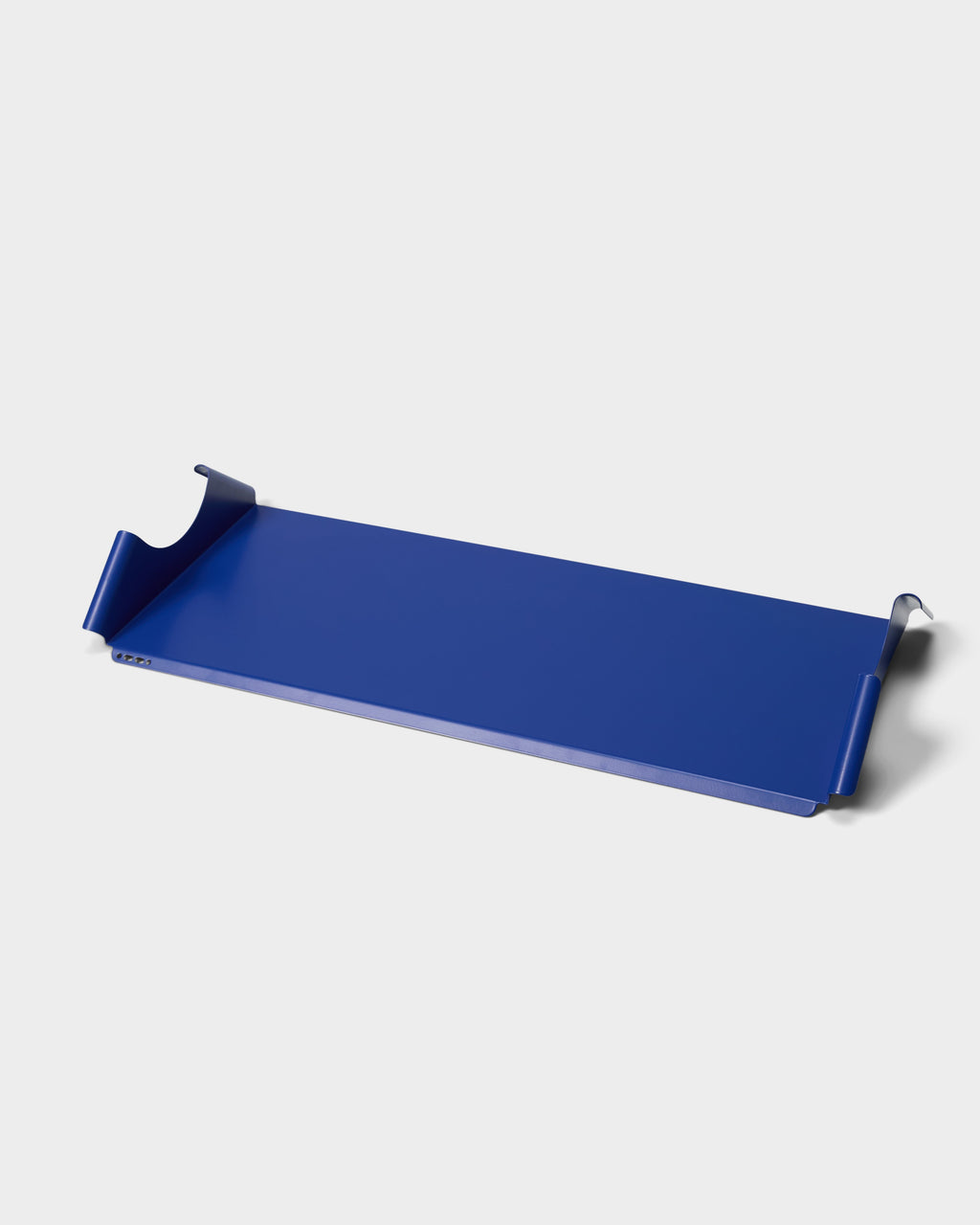 Moon Tray Shelf in Ultra Marine shown at an angle on a white studio backdrop, highlighting its folded steel edges