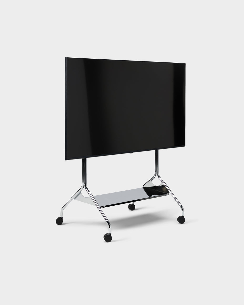 Moon Tray Shelf in Chrome on a rolling TV cart with mounted flat screen, angled studio view showing casters