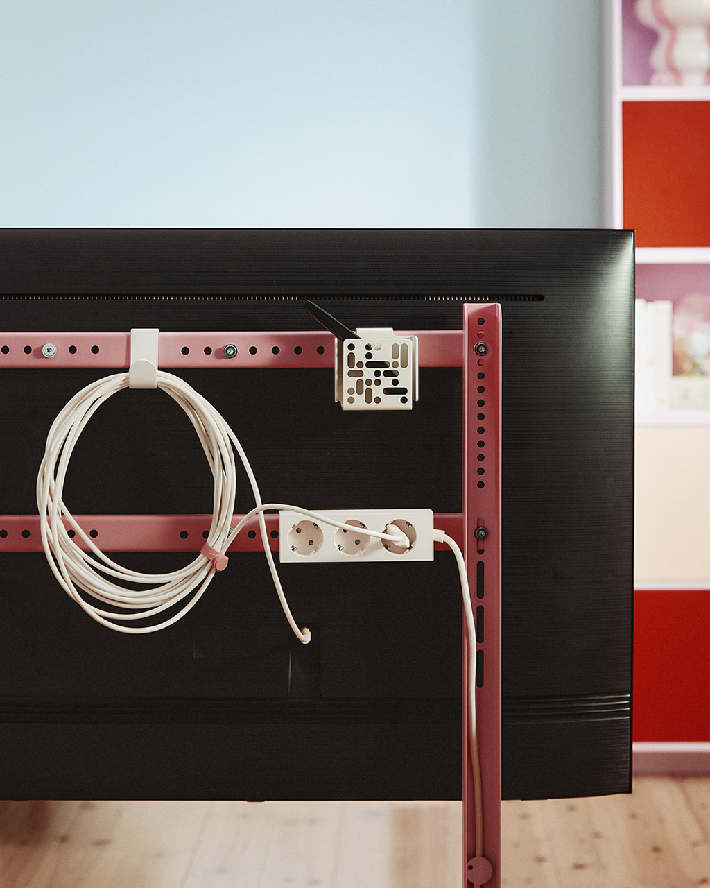 Rear view of TV on Mount Bundle in Pearl, showing pink rails with coiled cable, power strip and cable management