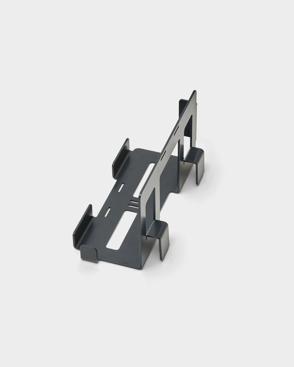 Charcoal PS5 Mount studio packshot at an angle, showing the folded steel cradle with slotted brackets and upright divider