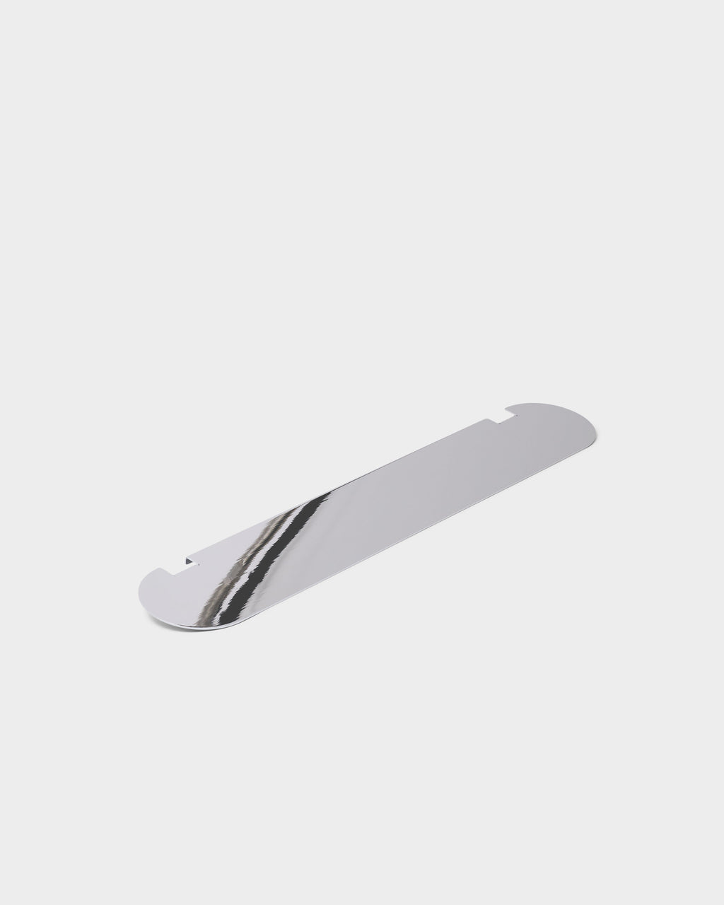 Moon Shelf in Chrome shown at an angle as a flat mirrored panel with rounded ends and notched edges on a studio backdrop