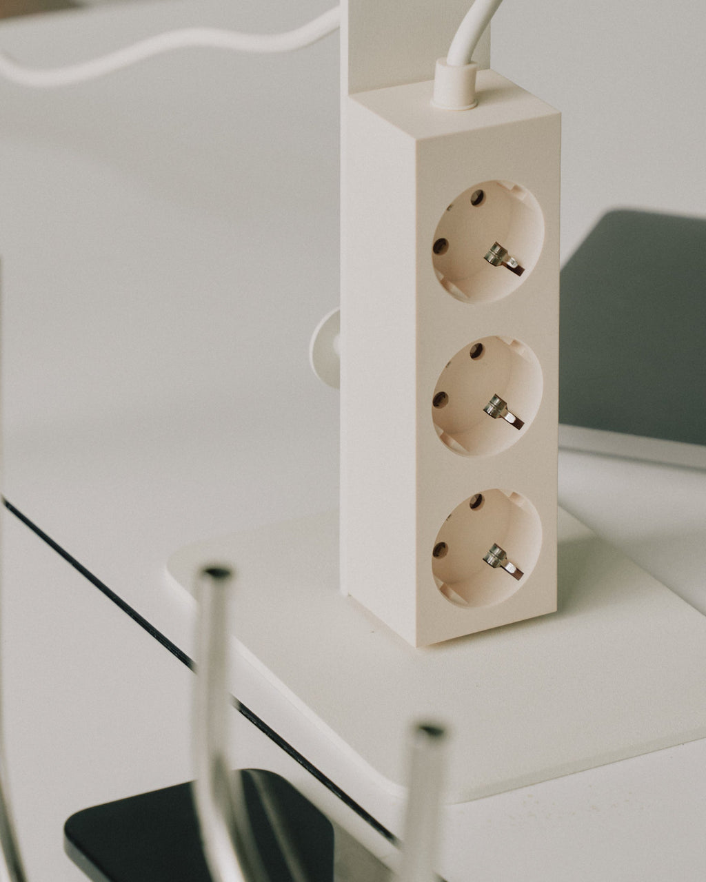 Pearl Power Tower standing upright on a white desk, angled close-up showing three recessed sockets and top cord