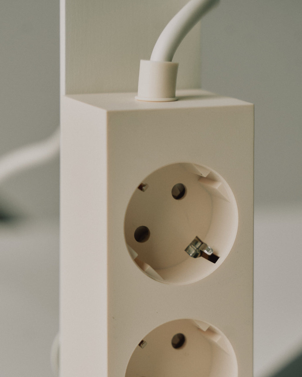 Close-up of Pearl Power Tower's grounded outlets and white cord exiting the top, shown against a soft neutral backdrop