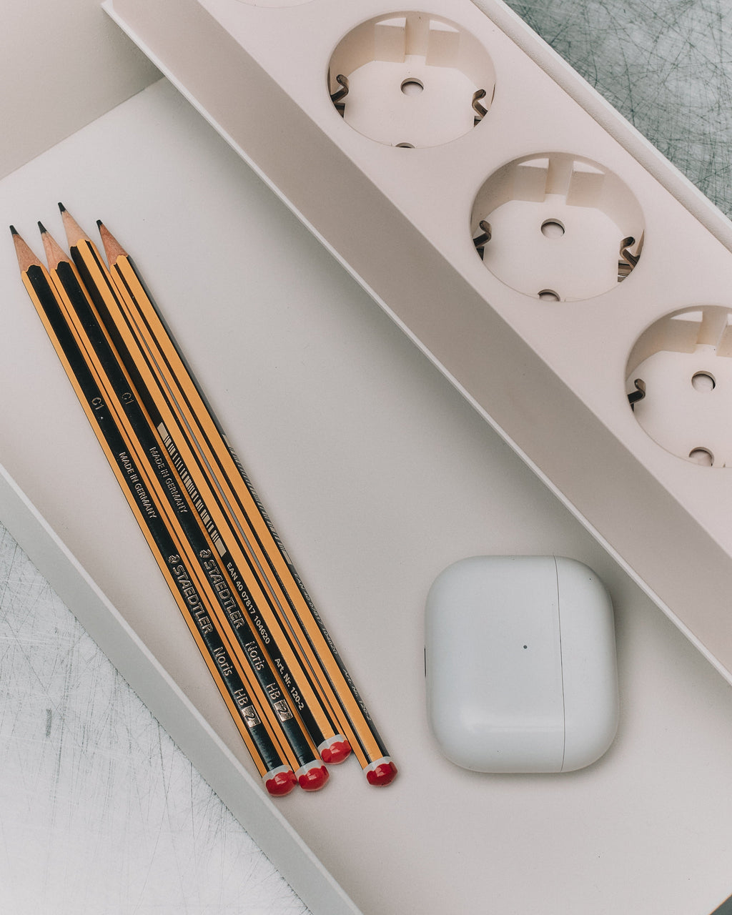 Pearl Power Beam Tray shown from above holding Staedtler pencils and white earbud case beside three power outlets