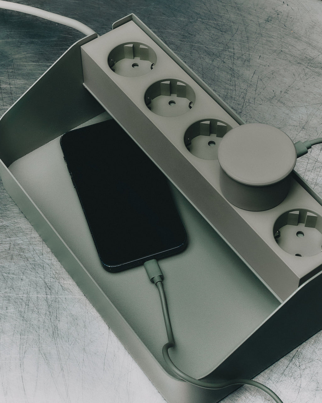 Power Beam Tray in Mossy Green holding a charging smartphone and puck charger, four sockets shown from above