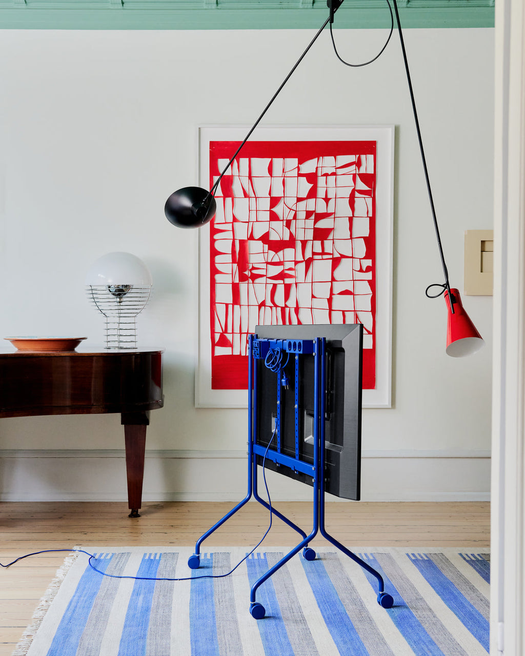 Ultra Marine Remote Box Mount on wheels holding a folded flat screen in a bright living room with red artwork