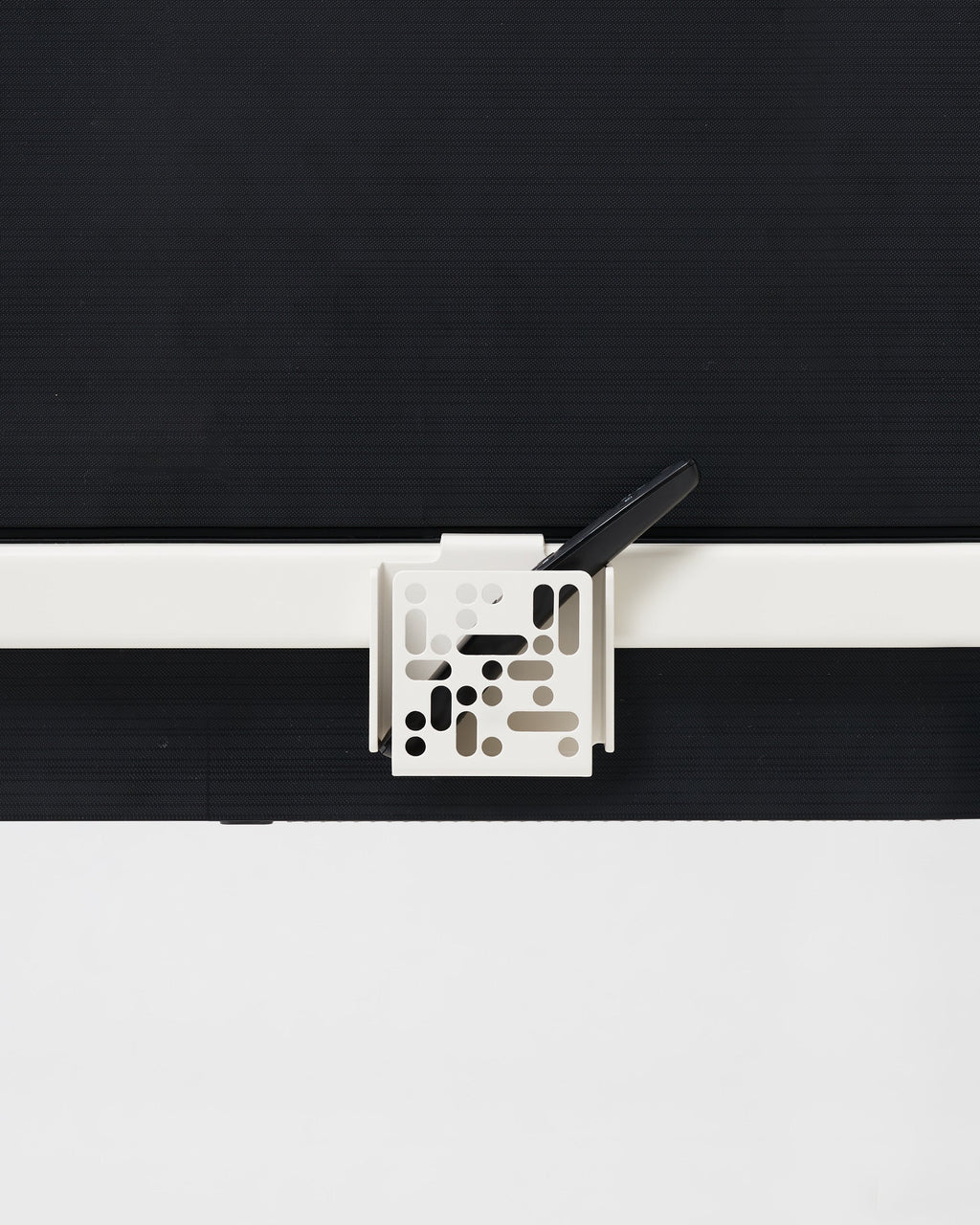 Pearl Remote Box Mount clipped to a TV frame edge, holding a black smartphone upright in a studio setup
