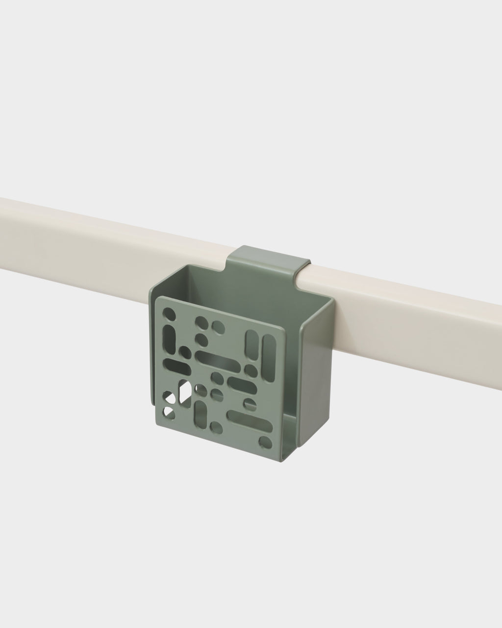 Remote Box Mount in Mossy Green hooked over a cream rail, studio packshot showing perforated front panel at an angle