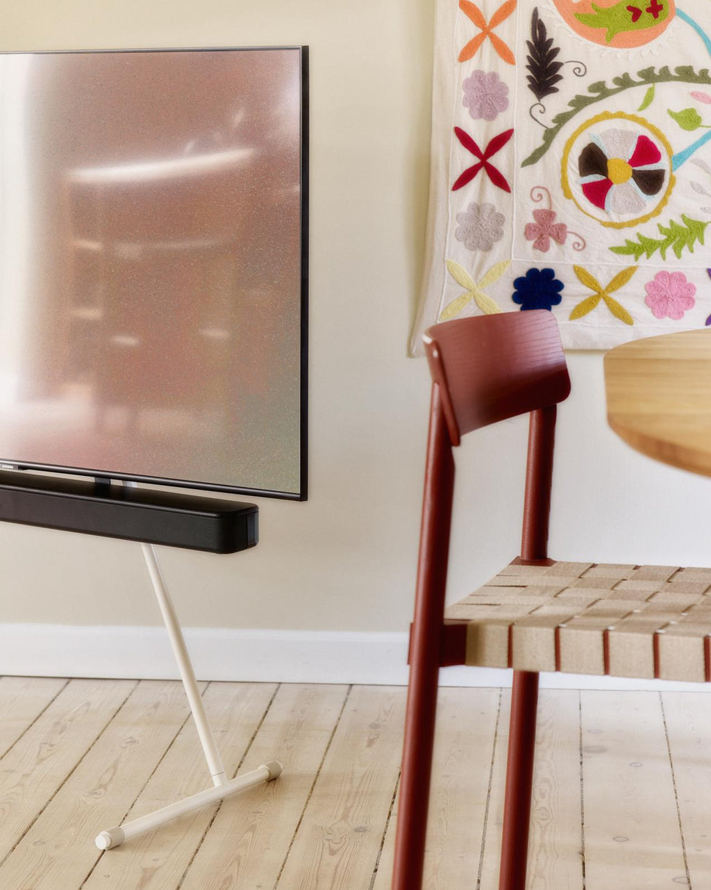 Soundbar Bracket Set in Charcoal holding a soundbar beneath a floor-stand TV in a bright wood-floored living room