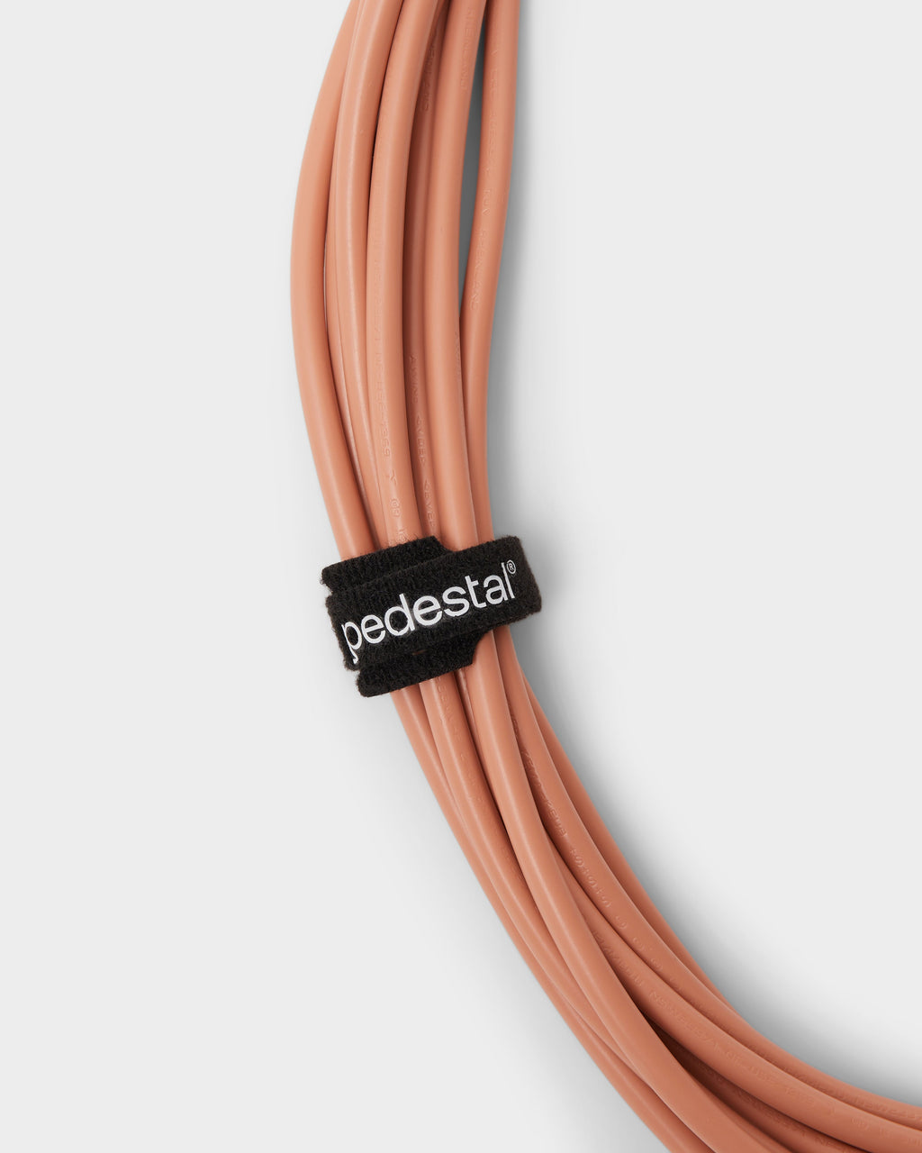 Black Velcro Cable Tie with white logo securing a coiled terracotta cord, close-up studio packshot on...