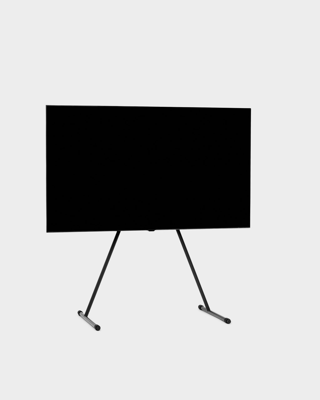 Viva TV stand in Charcoal holding a large flat-screen TV, angled studio packshot showing splayed tripod legs