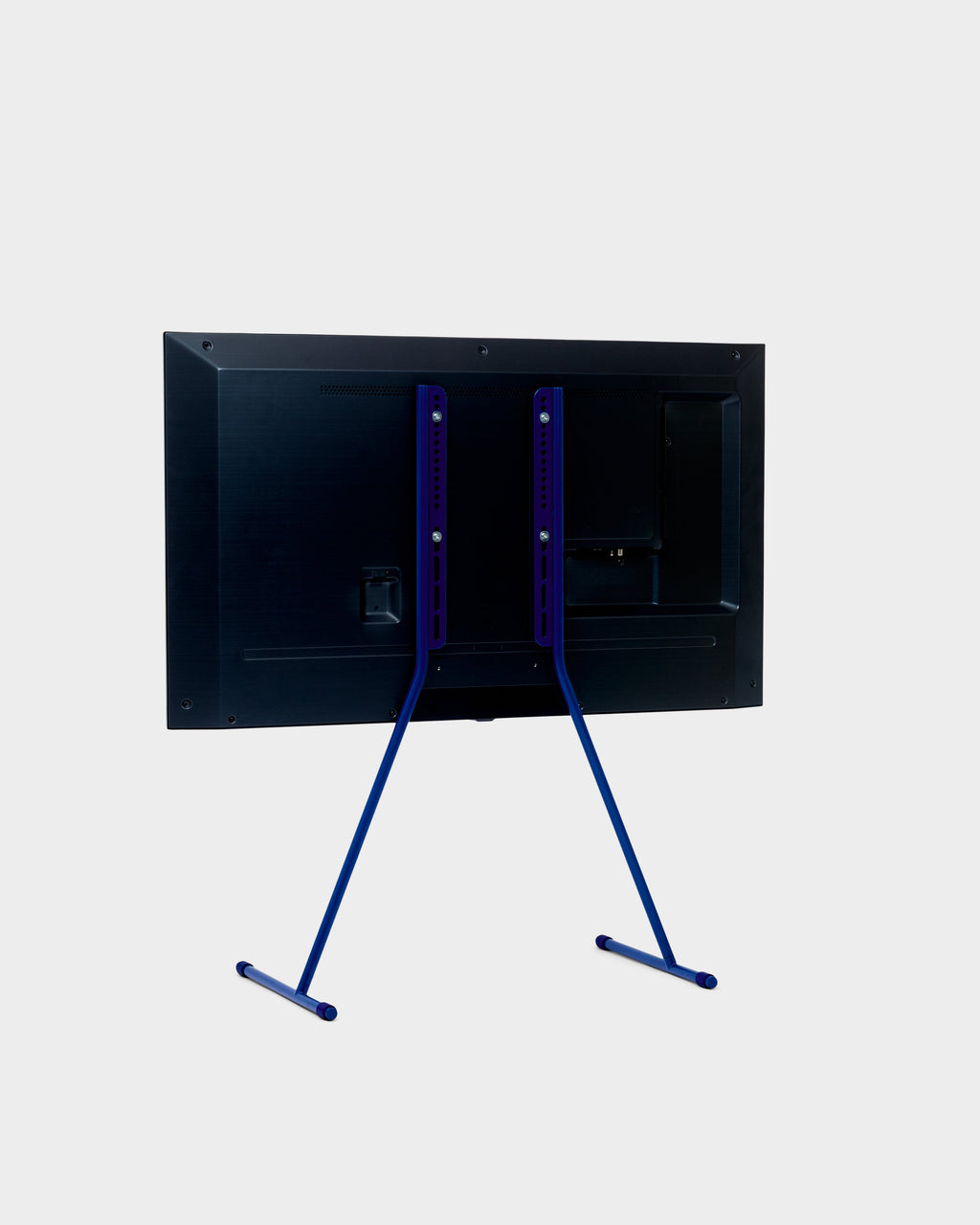 Rear three-quarter view of the Viva TV stand in Ultra Marine holding a mounted flat-screen TV on a studio backdrop