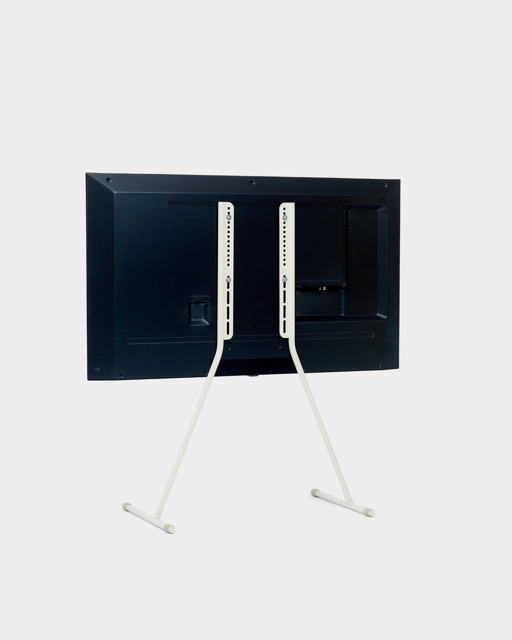 Rear view of Viva TV stand in Pearl holding a mounted flat-screen TV, showing slim white legs and T-shaped feet