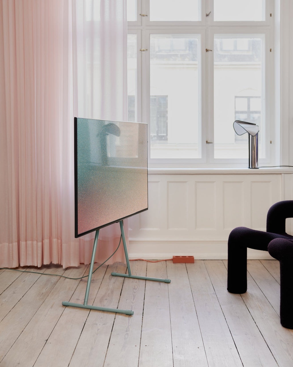 Viva TV stand in Mossy Green holding a flat-screen TV in a bright room with pink curtains and pale wood floors