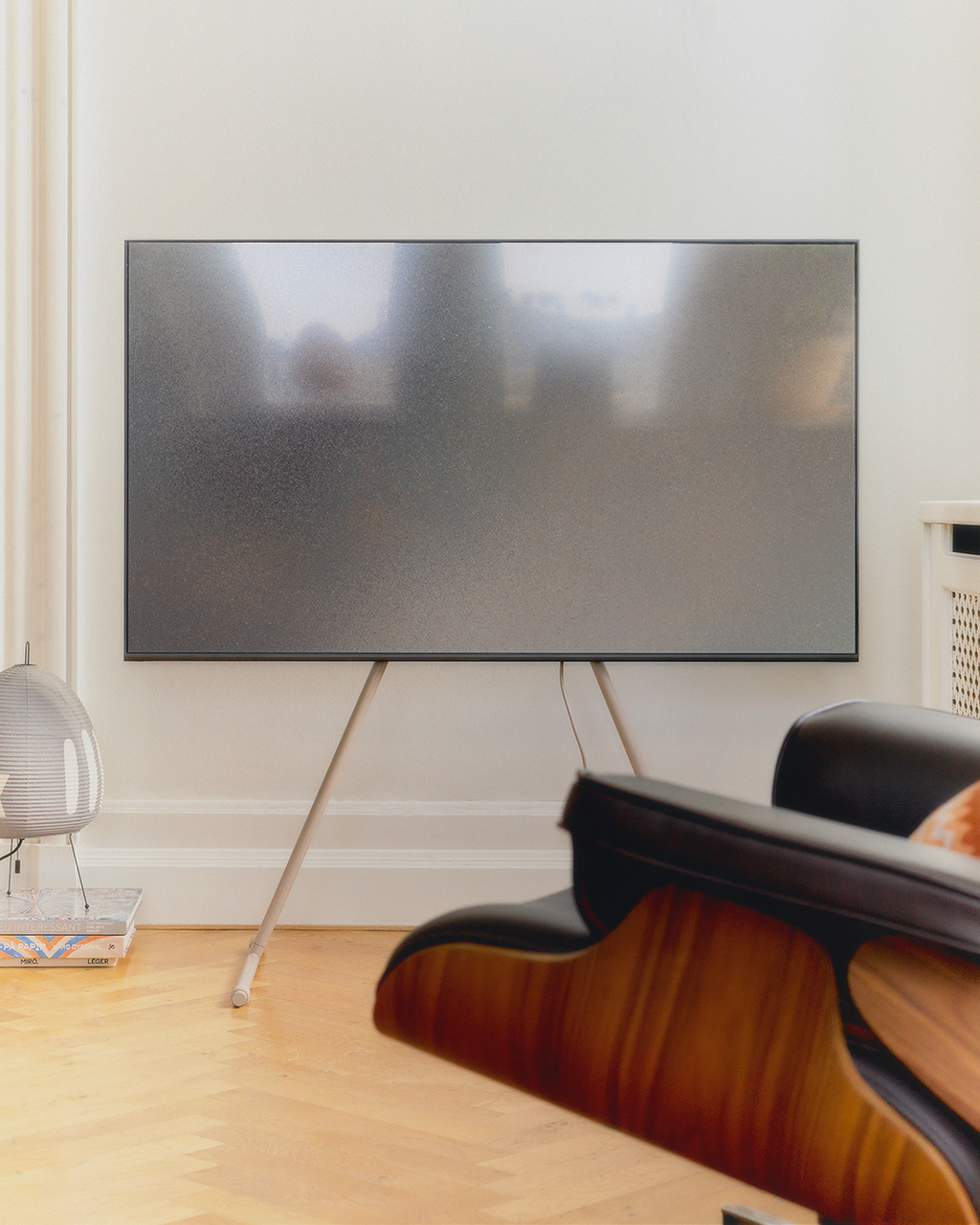 Viva TV stand in Oat holding a large flat-screen in a bright living room with parquet floors and a leather lounge chair