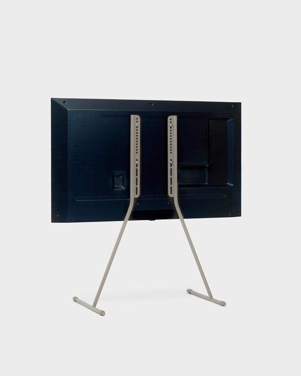 Rear three-quarter view of Viva TV stand in Oat holding a mounted flat-screen TV, studio packshot on light grey