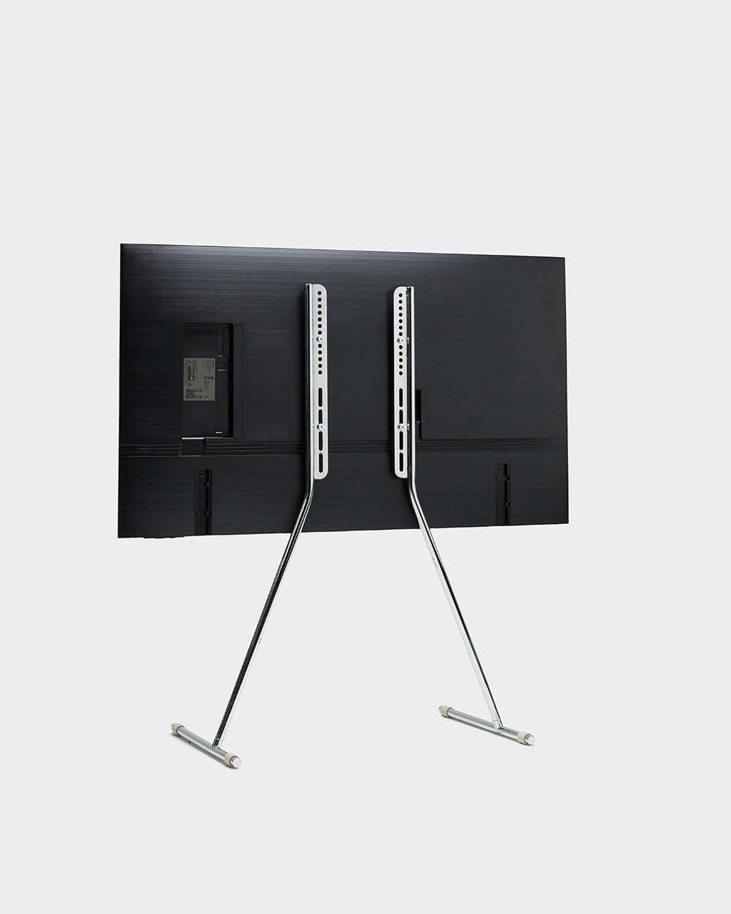 Rear view studio shot of the Viva TV stand in chrome holding a mounted flat-screen TV on slim angled legs